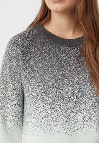 Ekskluzywny sweter z gradientowym wzorem o błyszczącej fakturze, przechodzący od jasnoszarego do ciemnoszarego, z okrągłym dekoltem i ściągaczami przy rękawach.