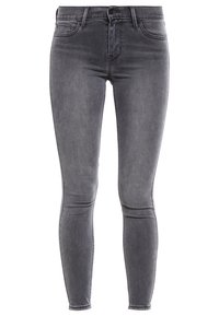 Jeans skinny grigi in denim, con chiusura frontale a bottoni, passanti per cintura e una finitura sbiadita con dettagli di whiskering sottili.