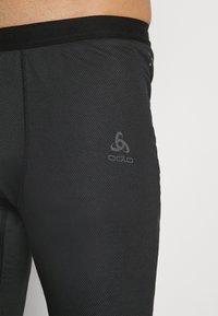 Schwarze Sportleggings mit Netzstruktur, elastischem Bund und dezentem Logo auf der unteren linken Seite. Glattes, eng anliegendes Design.