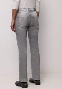 Grijze spijkerbroek van denim met een rechte pijp, voorzien van twee achterzakken en een subtiele vervaagde uitstraling. Gecombineerd met zwarte enkellaarsjes met hak.