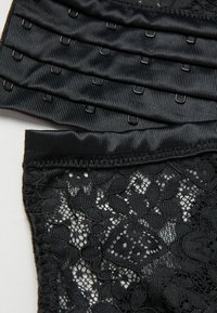 Zwarte lingerie met een textuur van kant en een soepel satijnen tailleband. Verstelbare haak-en-oogsluitingen zijn zichtbaar aan één kant.