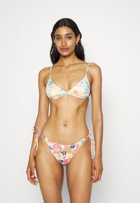 Conjunto de bikini floral com top de triângulo com alças finas e braguitas de amarrar ajustáveis, feito em tecido texturizado em cores pastel.