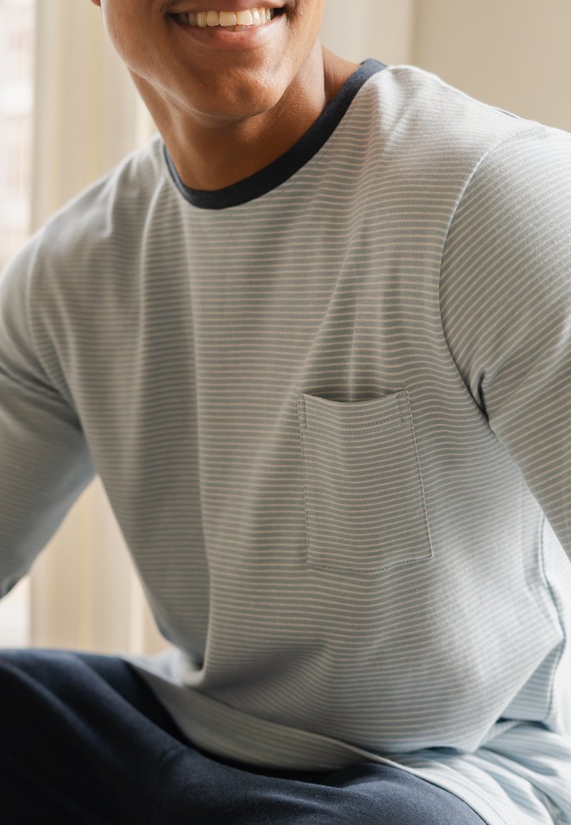 Lichtblauw overhemd met lange mouwen en witte strepen, zwarte halslijn en een enkele borstzak. Glad stofmateriaal, ontspannen pasvorm.