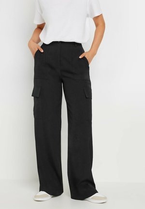 Zwarte cargo-broek met wijd rechte pijpen, voorzien van twee voorkeurszakken en twee zijzakken, met een zachte textuur en een casual pasvorm. Gecombineerd met witte sneakers.