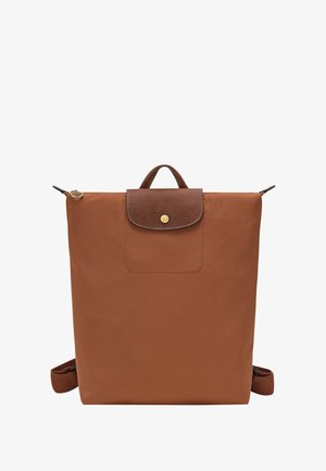 Square-shaped rust orange backpack with brown leather flap and handle, gold button, and adjustable shoulder straps.