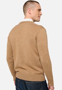 Beiger Strickpullover mit langen Ärmeln und geripptem Saum. Aus weichem Material gefertigt, mit klassischem Rundhalsausschnitt und glatter Textur.