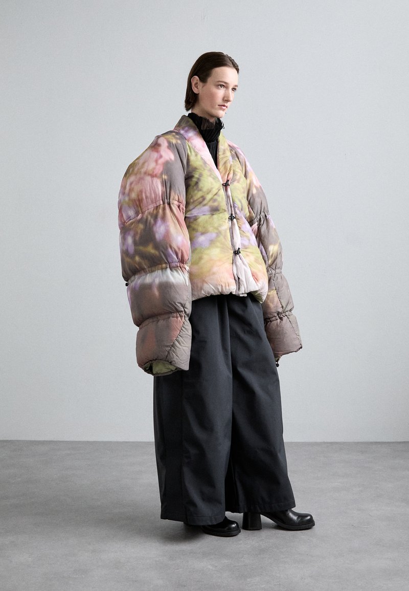 Bundučková bunda s květinovým potiskem v pastelových barvách, s oversize rukávy a krátkým střihem. V kombinaci s širokými černými kalhotami a platformovými botami.