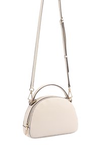 Sac à main en cuir couleur crème en forme semi-circulaire avec des fermetures éclair dorées, une bandoulière ajustable détachable et une petite poignée sur le dessus.