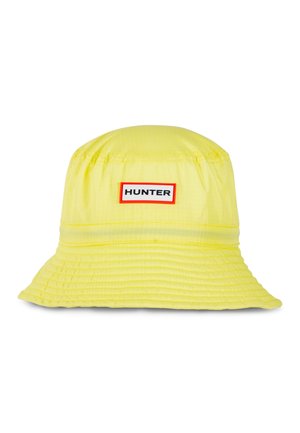 Żółty kapelusz typu bucket z przeszywanym rondem i prostokątną białą metką obramowaną na czerwono z napisem „HUNTER” czarnymi literami.