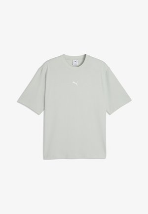 Lysgrå t-shirt med korte ærmer og et lille hvidt Puma-logo centreret på brystet, lagt fladt ud på en ensfarvet hvid baggrund.