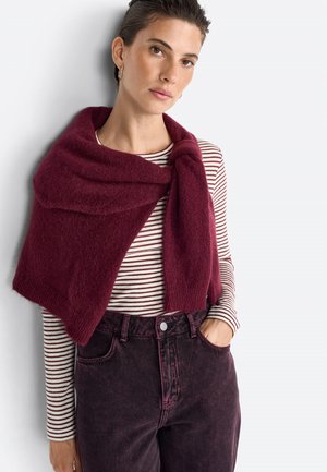 Burgundy knitted scarf draped over a striped shirt. Model wears dark pink high-waisted jeans. Soft texture, casual layered look.