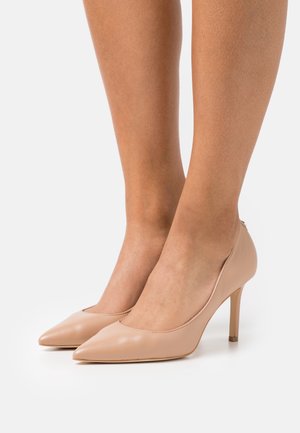 Escarpins en cuir couleur nude avec bout pointu, talon aiguilles fin, texture lisse et design minimaliste.