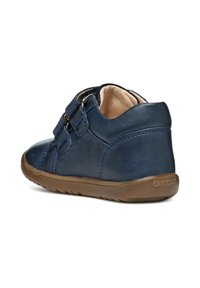 Zapato de cuero azul marino con doble cierre de correa, punta redondeada y suela de goma marrón con detalles texturizados. Marca Geox visible.