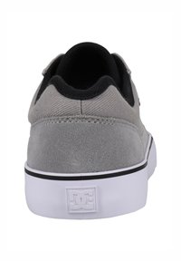 Grå mocka skate skor med svarta detaljer, vit gummisula och DC-logga på hälen. Rundad tå och vadderad krage för komfort.