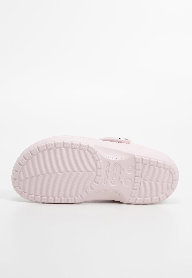 Zapato cerrado de color rosa claro con suela de goma texturizada, que presenta un diseño simple y un patrón de piso pronunciado para mayor tracción.