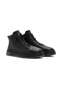 Sneakers alte in pelle nera con suola testurizzata, dotate di lacci rotondi e design della punta liscia. I dettagli includono il logo sulla linguetta.
