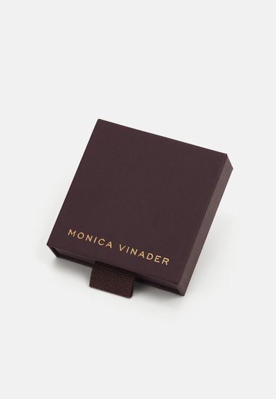 Dark purple rigid jewelry box with a textured finish, featuring a gold embossed logo "MONICA VINADER" and a fabric pull tab.