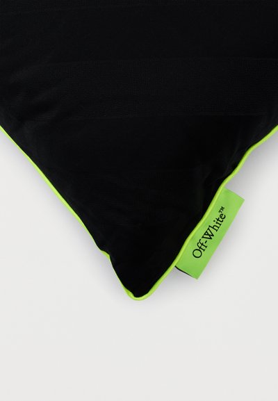 Μαύρο τριγωνικό μαξιλάρι με πράσινη νέον περίγραμμα και πράσινη νέον ετικέτα που εμφανίζει το όνομα της μάρκας «Off-White™» σε λευκό φόντο.