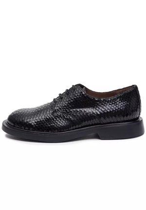 Czarne skórzane eleganckie buty męskie z fakturą przypominającą skórę węża i czarną gumową podeszwą, widziane z boku.