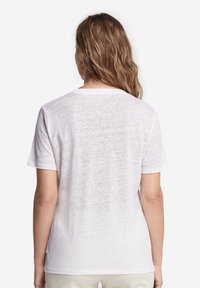 Vit t-shirt med kort ärm och rund hals, tillverkad av lätt, något genomskinligt tyg, med avslappnad passform och utan synlig logotyp.