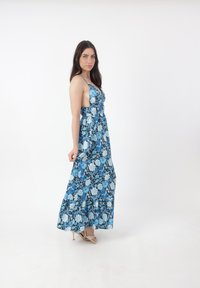 Robe maxi en imprimé floral bleu, avec des bretelles spaghetti, un corsage ajusté, une jupe fluide et un ourlet volanté. Tissu doux avec une texture légère.