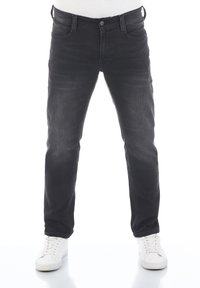Jeans de mezclilla negra con un diseño ajustado, que cuentan con un estilo clásico de cinco bolsillos, un ligero desvanecimiento y un cierre de botón. Llevados con zapatillas blancas.