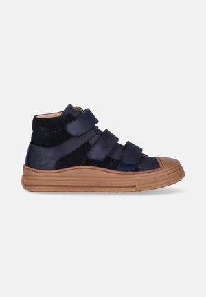 Marineblauwe hoge sneaker met drie brede klittenbandsluitingen en een dikke bruine rubberen zool, zijaanzicht op een witte achtergrond.