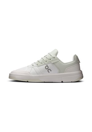 Baskets blanches basses avec des accents gris clair, lacets à l'avant, bout perforé et un logo gris "oc" sur le côté.