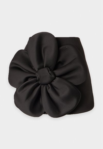 Bandeau en tissu noir avec une grande décoration florale douce à cinq pétales au centre.