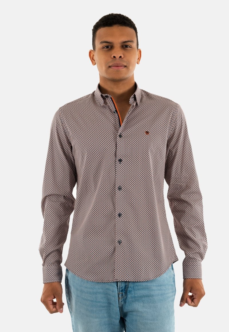Chemise à manches longues en tissu à motifs avec des motifs de diamants rouges et bleus, un col boutonné et un contraste orange à l'intérieur du col.