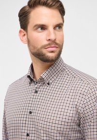 Camicia button-up a scacchi marroni e blu, realizzata in cotone. Presenta un colletto a punta, una tasca sul petto e bottoni neri.