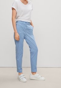 Ljusblå chinos med slim fit, bälteshällor och sidofickor, kombinerat med en vit t-shirt med korta ärmar och vita sneakers.