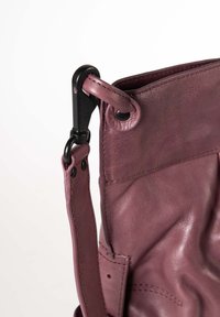 Borsa a tracolla in pelle di un viola tenue con finitura testurizzata. Caratterizzata da un clip in metallo nero, una tracolla cucita e un'ampia apertura senza chiusura visibile.