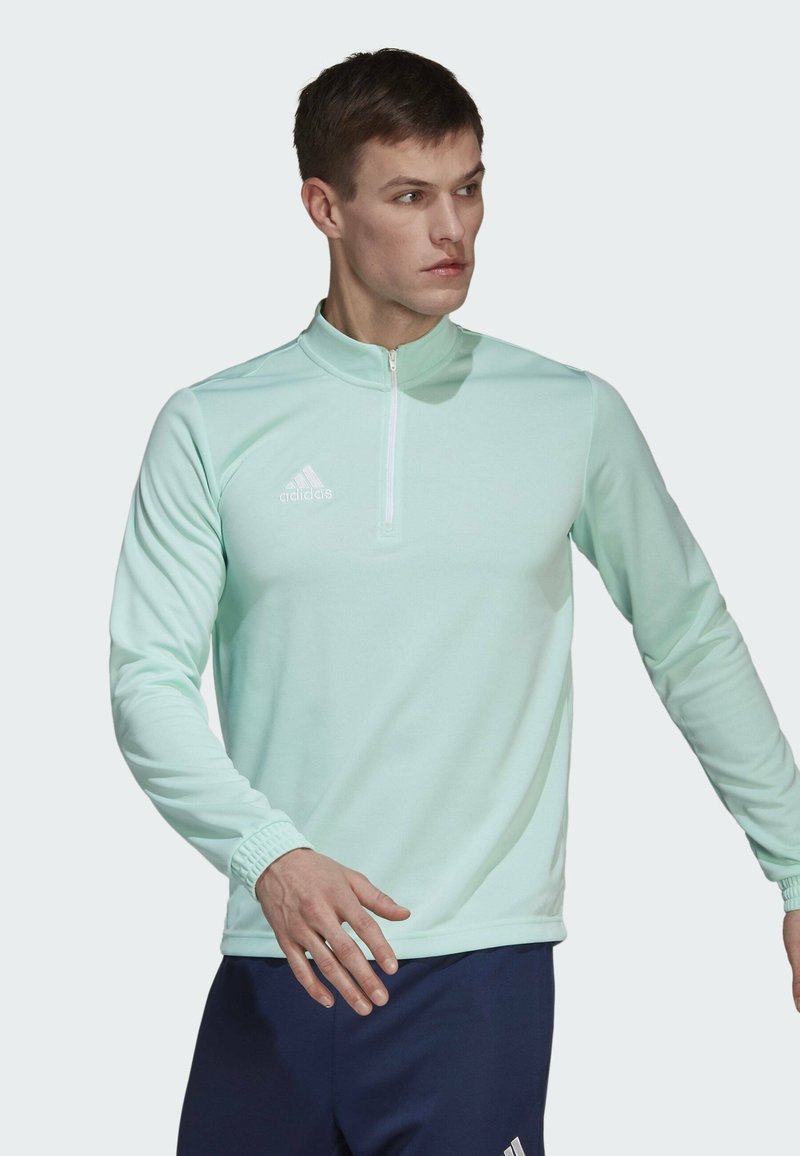 Mintgrünes, langärmliges Sportoberteil mit einem Viertelreißverschluss-Design, das ein weißes Adidas-Logo auf der linken Brust und gerippte Bündchenakzente aufweist.
