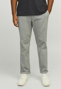 Light grey cotton trousers with a straight cut, featuring rolled cuffs and side pockets, paired with white sneakers.