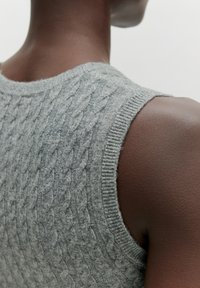 Grau gestrickter ärmelloser Pullover mit einem Zopfmuster, geripptem Halsausschnitt und glatter Textur. Fokus auf Details an Schulter und Rücken.