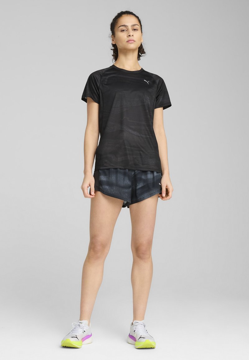 Must-haves must must have must have must have a black athletic t-shirt with a textured pattern, paired with black shorts featuring a subtle sheen. White and purple sneakers with green accents.
