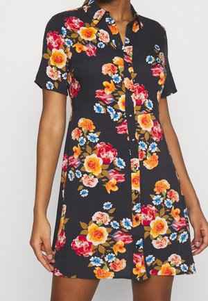 Czarna sukienka z krótkim rękawem i guzikami, zdobiona dużymi, żywymi kwiatowymi wzorami w kolorach żółtym, czerwonym, niebieskim oraz zielonym liściem.