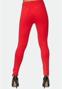 Röda leggings i stretchtyg med en slät yta, två bakfickor och hög midja. Matchas med svarta högklackade skor.