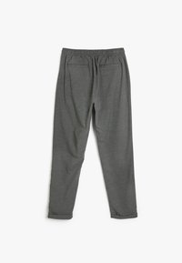 Pantalones grises, ajustados en un tejido suave con una cintura elástica. Presenta dos bolsillos traseros y dobladillos enrollados en los tobillos.