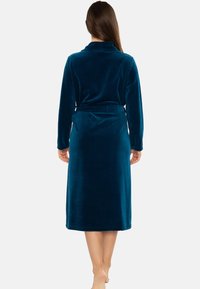 Accappatoio lungo teal realizzato in morbido tessuto peloso. Presenta un colletto a scialle, maniche lunghe e una cintura da annodare in vita. Texture liscia con un design lungo fino al pavimento.