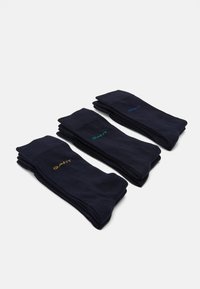 Tres pares de calcetines de un azul marino oscuro, con diferentes colores de logotipos (verde, azul y amarillo) en los puños, textura suave y diseño sencillo.