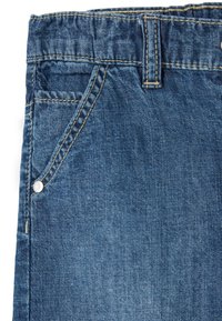 Vaqueros de denim con un lavado azul oscuro, que presentan un bolsillo frontal, detalle de botón y costuras a lo largo de la cinturilla y las costuras.
