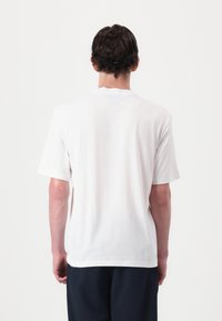 White cotton t-shirt with short sleeves, crew neckline, and a relaxed fit. No visible patterns or graphics on the back.