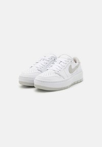 Sneaker bianche in pelle con un accento grigio testurizzato e suola imbottita. Presentano dettagli perforati sulla punta e lacci piatti.