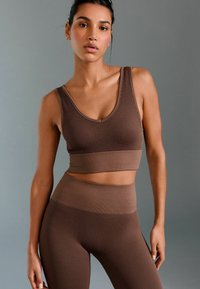 Brown ribbed athletic crop top paired with matching high-waisted leggings, featuring a textured pattern and fitted design.