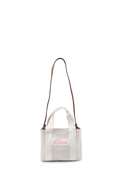 Borsa in tela di un beige chiaro con due manici superiori e una tracolla rimovibile. Presenta il logo "Chloé" in rosa embossato sul fronte.