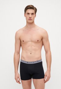 Schwarze Boxershorts aus Baumwollmix mit einem grauen Elastikbund und dem Schriftzug "PIER ONE". Elegantes, figurschmeichelndes Design.