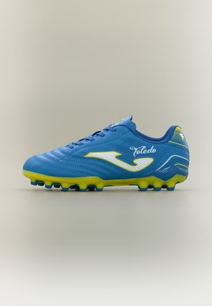Blauw-gele voetbalschoen met studs, met "Toledo" en een wit logo aan de zijkant, afgebeeld tegen een neutrale achtergrond.