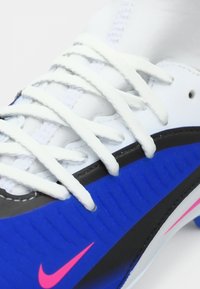 Λευκό αθλητικό παπούτσι με μπλε και μαύρες λεπτομέρειες και ροζ λογότυπα Nike Swoosh στο πλάι και στη σόλα.